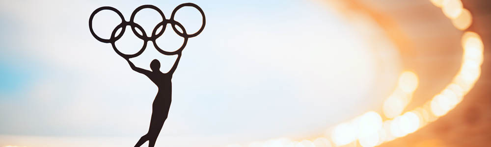 Olympic statue in the foreground with the Paris Olympic stadium in the background, blue sky with clouds in the sky